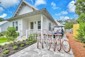 Una casa blanca con porche, un aparcamiento para bicicletas y un jardín bien cuidado.