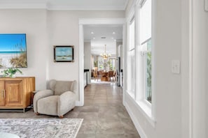 A modern interior with a neutral color palette, a dining area with a chandelier, and a view through large windows. - Coastal Reset by Stay on 30a (Seacrest)