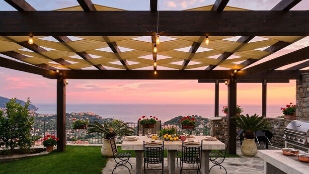 Eine Terrasse im Freien mit Esstisch, Grill und Blick auf die Landschaft.