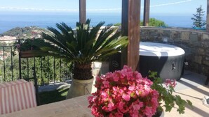 Eine Terrasse mit Meerblick, einem Whirlpool und Kübelpflanzen.