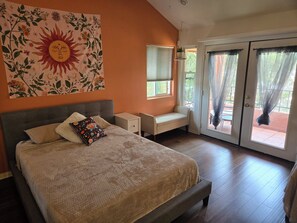 A bedroom with a bed, a nightstand, a bench, a window, and a sliding glass door. - Sunny and Spacious 5‑Bedroom San Diego Retreat - Walkable Near SDSU (San Diego)