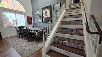 A staircase with motivational phrases, a dining area with chairs and a table, and a window with a view.