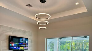 Una sala de estar moderna con un televisor de pantalla plana, muebles de cuero, un ventanal y vista a la piscina.