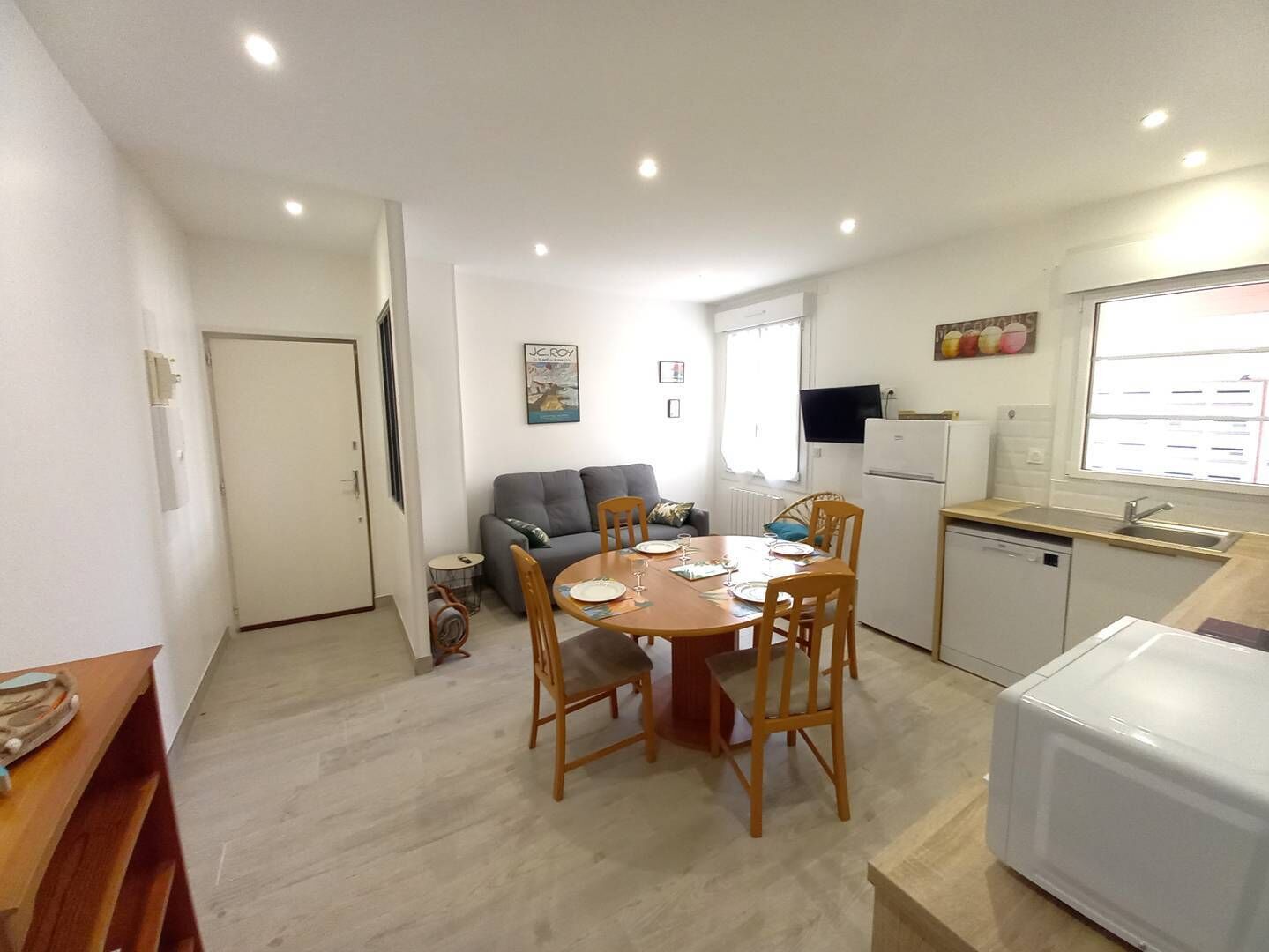Una cocina compacta con una mesa de comedor, sillas, sofá y refrigerador.