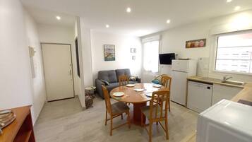 Una cocina compacta con una mesa de comedor, sillas, sofá y refrigerador.