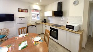 Una cucina funzionale con microonde, piano cottura, lavello e una sveglia appesa al muro.
