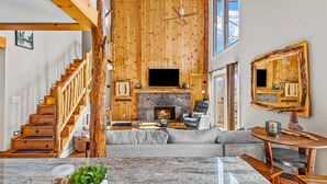 A spacious living area with a stone fireplace, a large flat-screen TV, and a cozy seating arrangement. - Slopeside Lodge at Sugar Mountain - Ski In/Out, Views, Near Water, Gas Fireplace (Sugar Mountain)