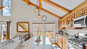A modern kitchen with wooden beams, a large island, and a view of the outdoors. - Slopeside Lodge at Sugar Mountain - Ski In/Out, Views, Near Water, Gas Fireplace (Sugar Mountain)