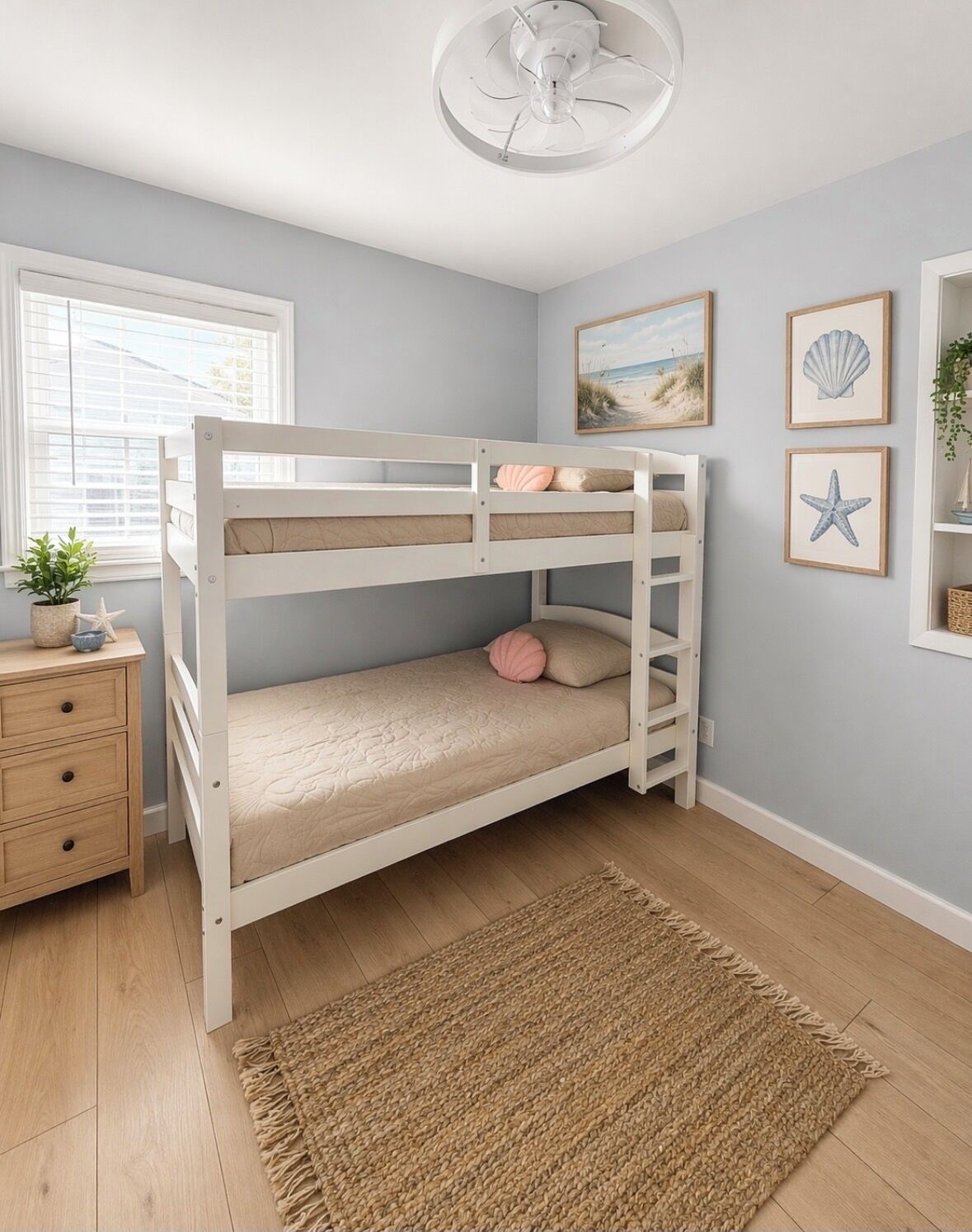 A bunk bed with a wooden frame, a bedside table with drawers, a small potted plant, and a wall with framed pictures.