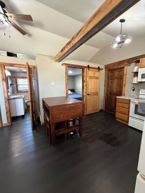 A kitchen with a wooden table, cabinets, and a ceiling fan.