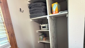 A narrow hallway with a wooden door, a small shelf with folded towels, and a box of tissues.