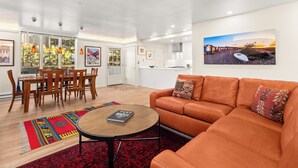 Una sala de estar moderna con un sofá, una mesa de centro y un área de comedor con sillas y alfombra.