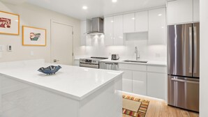 Una cocina moderna con armarios blancos, electrodomésticos de acero inoxidable y una isla de mármol.