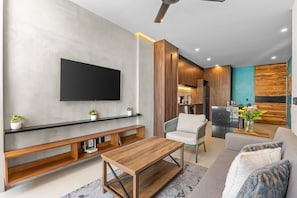 Ein modernes Wohnzimmer mit Fernseher, Holzmöbeln, einer Couch und einem Couchtisch.