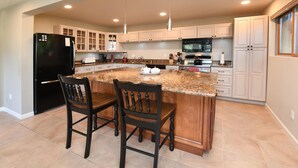 A kitchen with a central island, two chairs, a refrigerator, cabinets, and a microwave. - SF Bay Area: Private Luxury “Treehouse” Retreat (Pleasant Hill)