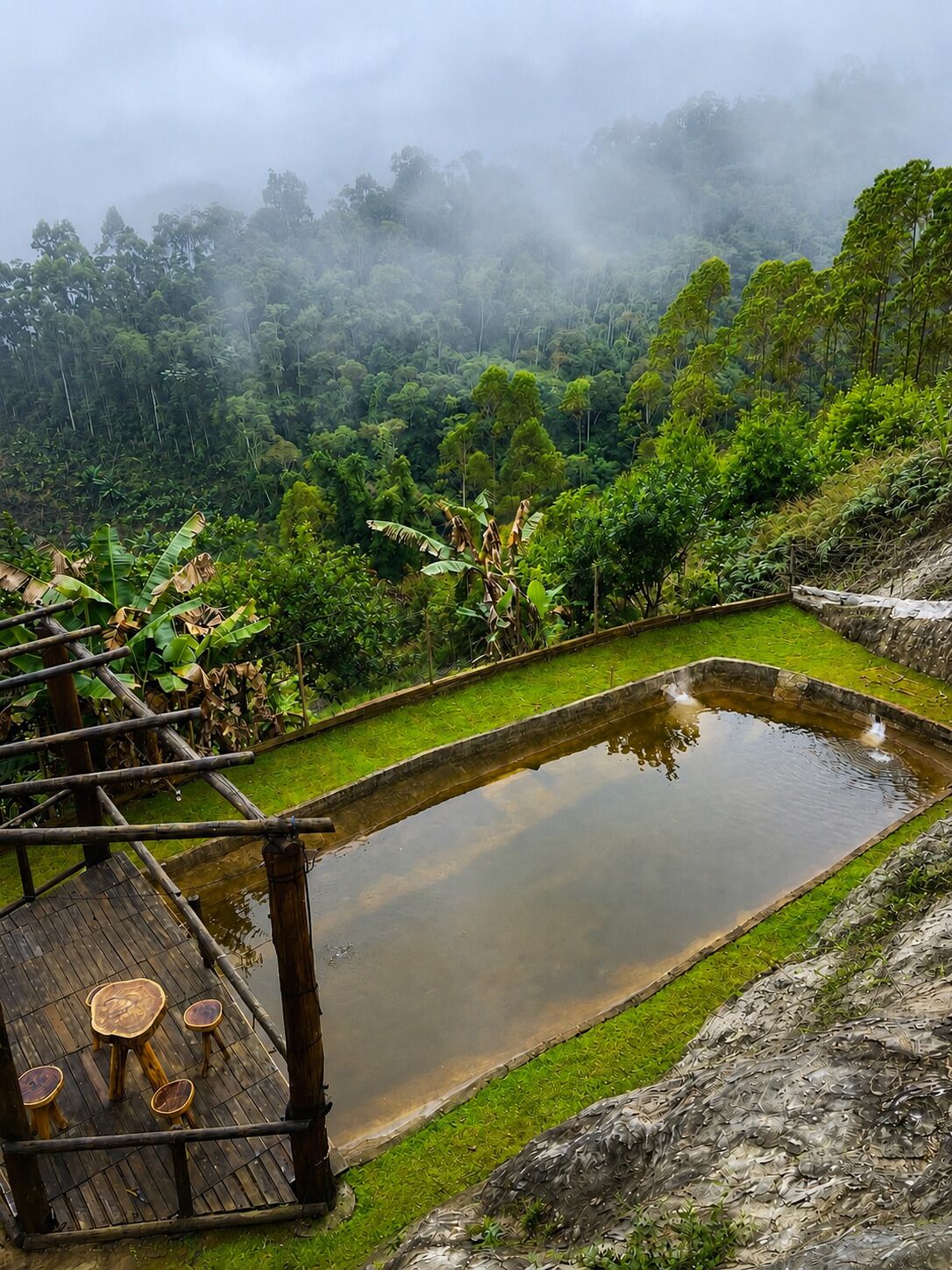 A terraced garden with a wooden deck and seating area overlooking a pond.