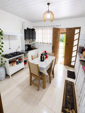 Una cocina con estufa, armarios y una mesa de comedor con sillas.