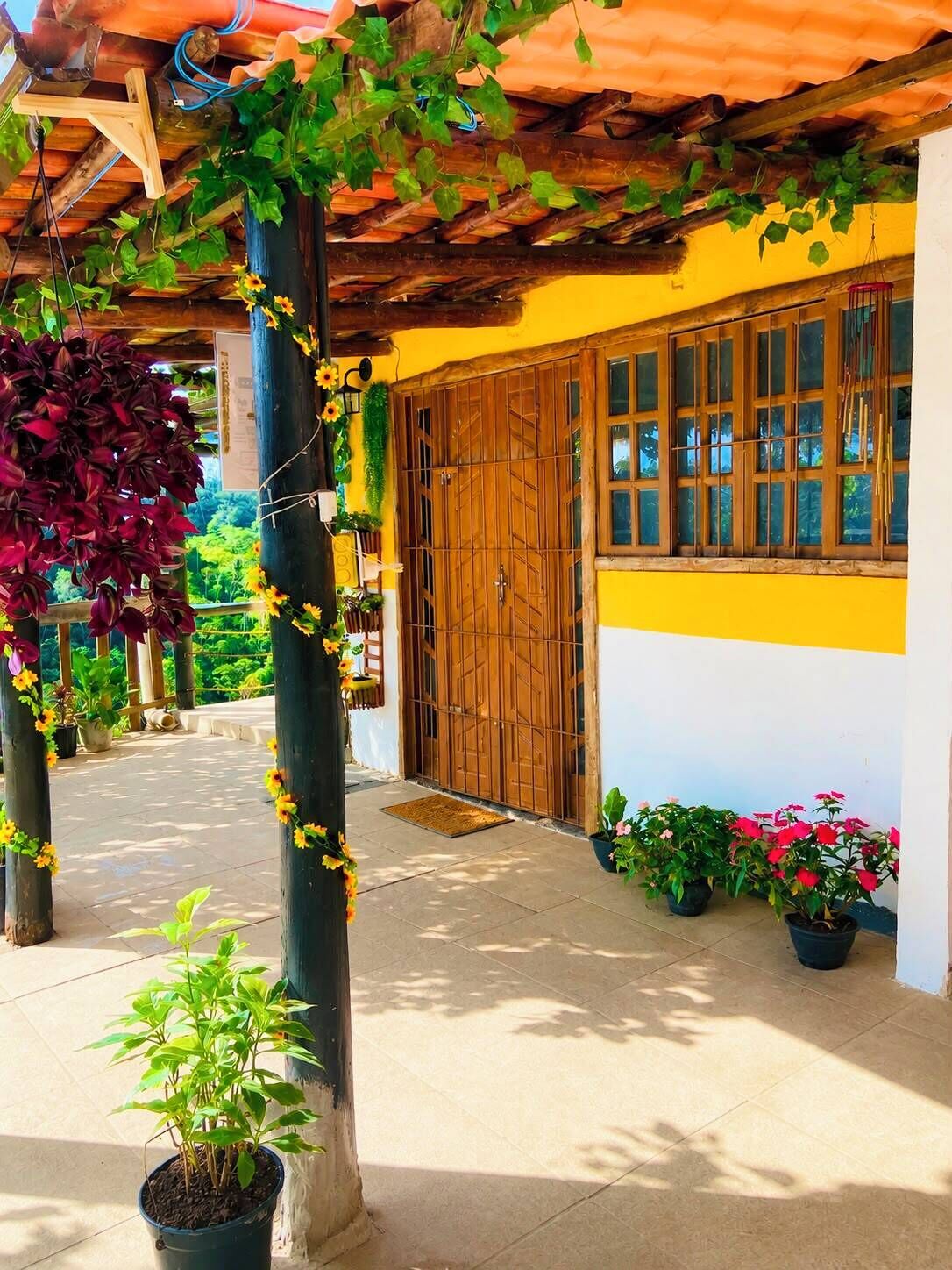 A covered outdoor area with a wooden door, potted plants, and a tiled floor.