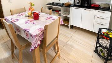 A compact kitchen with a dining table, chairs, and a variety of kitchen appliances and utensils.