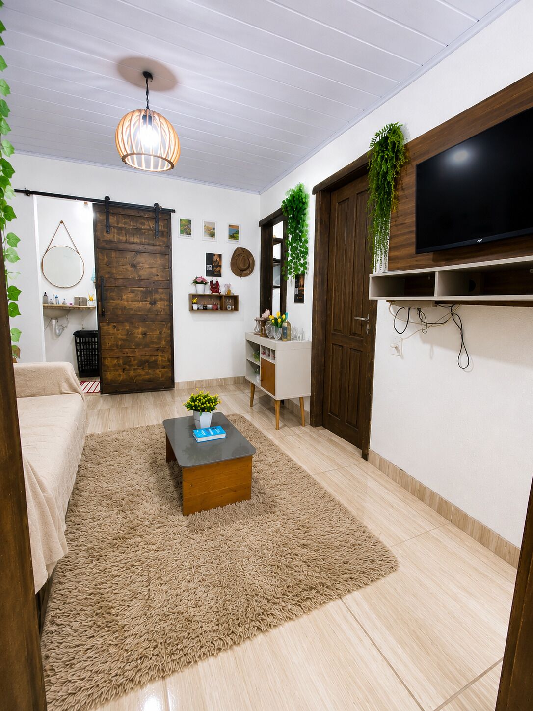 A living room with a sofa, coffee table, TV, and a wooden door.