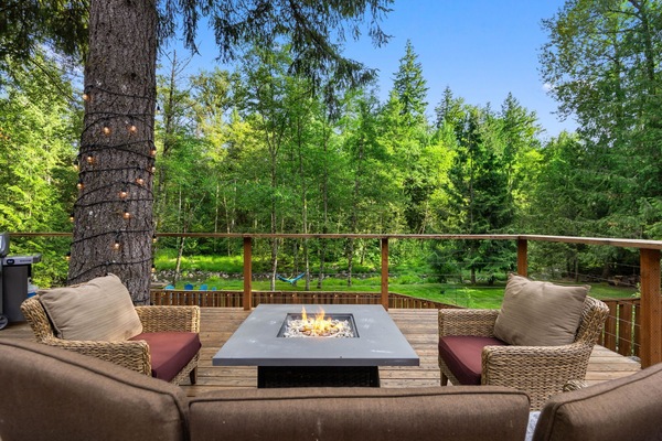 Private deck with fire pit, outdoor seating, and scenic forest views, perfect for a relaxing cabin getaway in nature.