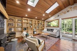 A cozy living room with a fireplace, wooden bookshelves, a sofa, and a coffee table. - Howard's Hideaway Riverfront Pet Friendly Cabin (Sandy)
