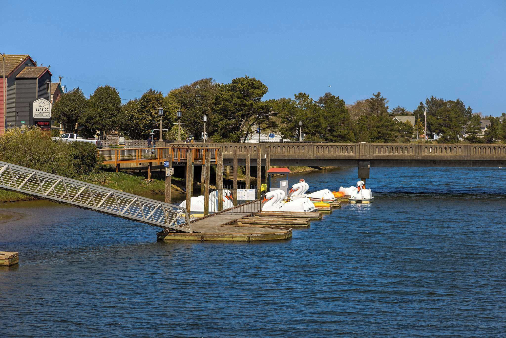 A bridge over water with swan-shaped boats docked on the right.
