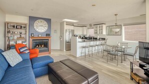 A modern living room with a fireplace, a dining area, and a kitchen.