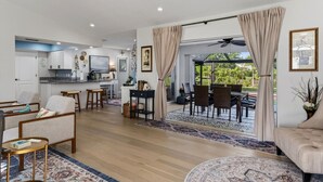A spacious living area with a kitchen, dining area, and a view of the outdoors. - The Salty Peacock near Englewood Beach (Rotonda West)