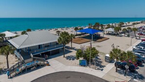 A beachside hotel with a large building, a parking area, and a view of the ocean. - The Salty Peacock near Englewood Beach (Rotonda West)