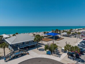A beachside hotel with a large building, a parking area, and a view of the ocean. - The Salty Peacock near Englewood Beach (Rotonda West)