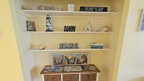 A room with a bookshelf, a welcome sign, and a small table with various items. - Pet friendly, waterfront property on a canal off of the Caloosahatchee River (Fort Myers)