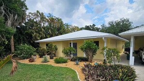 A yellow house with a covered porch, surrounded by a well-maintained lawn and various plants. - Pet friendly, waterfront property on a canal off of the Caloosahatchee River (Fort Myers)