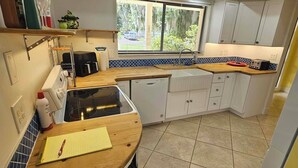 A kitchen with white cabinets, a wooden countertop, a window with blinds, and a ceiling fan. - Pet friendly, waterfront property on a canal off of the Caloosahatchee River (Fort Myers)