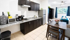 A modern kitchen with dark cabinets, a microwave, a refrigerator, and a dining area with a table and chairs. - CABO DOWNTOWN STUDIOS: 1BR Studio 2 doubles perfect location close to marina #3 (Cabo San Lucas)