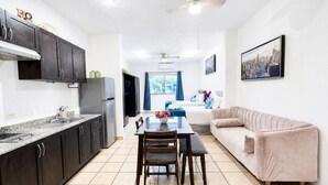 A modern kitchen with dark cabinets, a dining table with chairs, a sofa, and a ceiling fan. - CABO DOWNTOWN STUDIOS: 1BR Studio 2 doubles perfect location close to marina #3 (Cabo San Lucas)