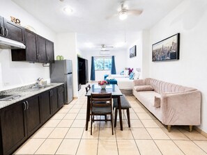 A modern kitchen with dark cabinets, a dining table with chairs, a sofa, and a ceiling fan. - CABO DOWNTOWN STUDIOS: 1BR Studio 2 doubles perfect location close to marina #3 (Cabo San Lucas)