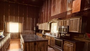 Une cuisine rustique avec des meubles en bois, un îlot central, une cuisinière et un four à micro-ondes.
