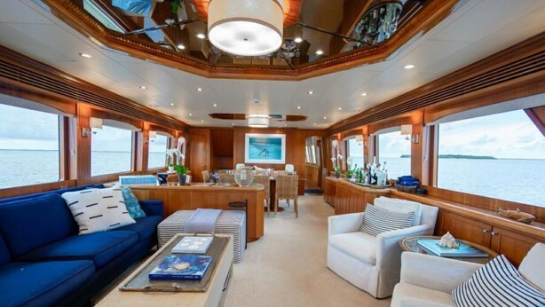 Interni di uno yacht con zona pranzo, un divano blu e un divano bianco.