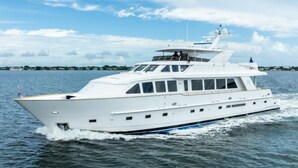Un grande yacht bianco con più ponti e finiture blu, che naviga in acque calme.