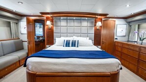 Un'ampia camera da letto con un letto grande, una testiera in legno e una zona salotto con divano.