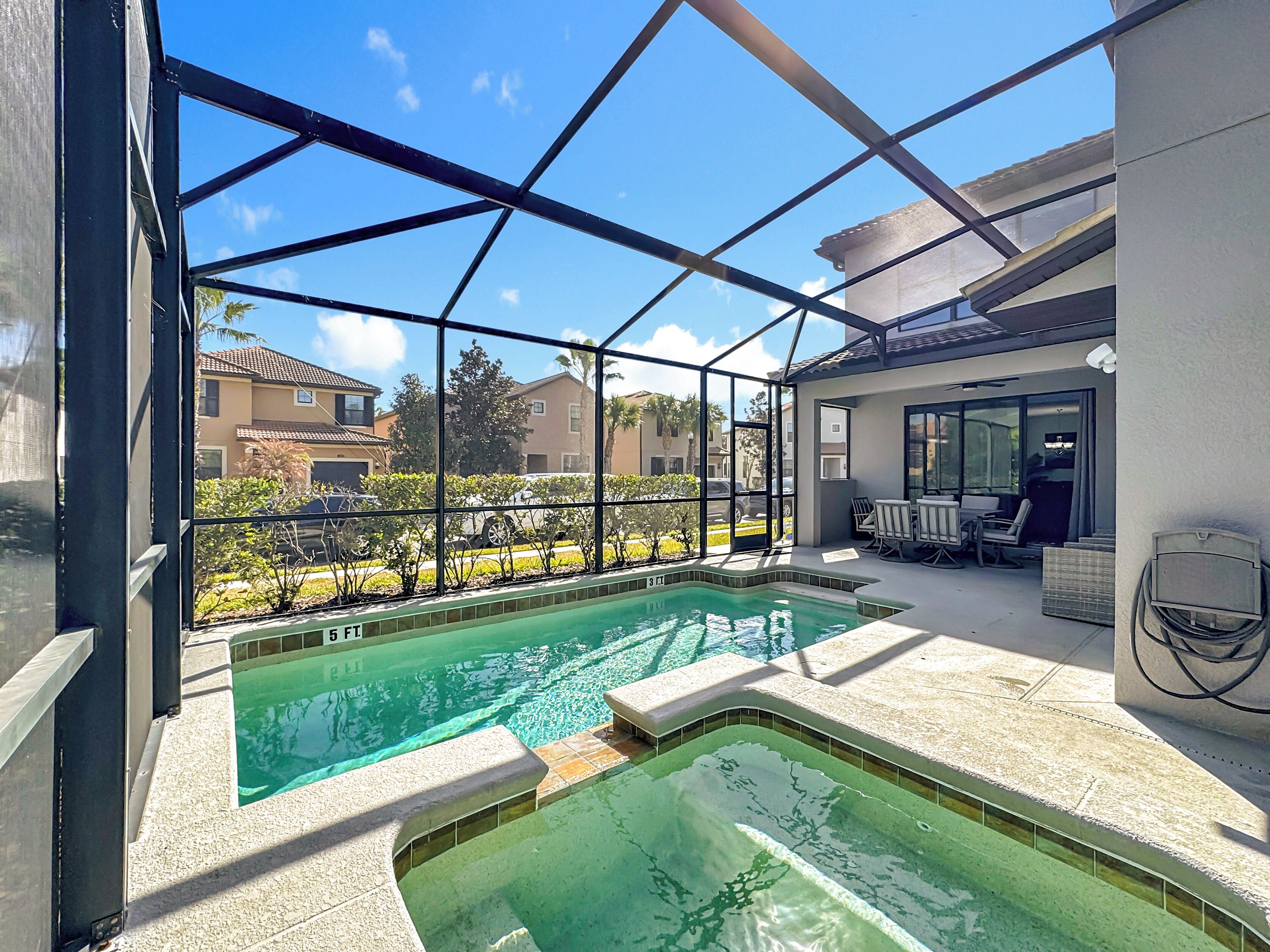 A swimming pool with a glass enclosure, outdoor seating, and a view of surrounding buildings.