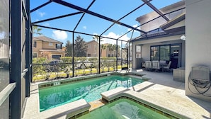 Ein Schwimmbad mit Glasveranda, Sitzmöglichkeiten im Freien und Blick auf umliegende Gebäude.