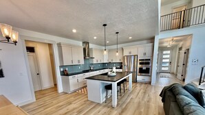 Una cocina moderna con una isla central, electrodomésticos de acero inoxidable e iluminación colgante.