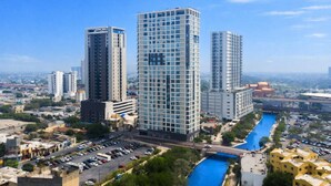 Un immeuble de grande hauteur doté d’une façade moderne en verre, entouré d’un parking et bordé d’un canal d’eau bleue.