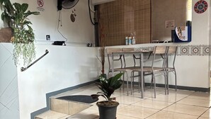 A kitchen area with a dining table, chairs, a potted plant, and a staircase leading to an upper level.