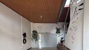 A spacious lobby with a wooden ceiling, tiled floor, and a reception desk with a plant.