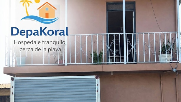 A building with a balcony, a security camera, and a closed shutter door.