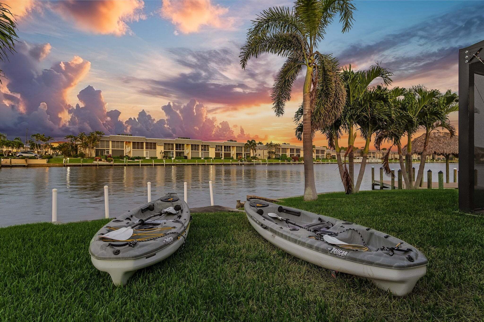 Deux kayaks sur l’herbe, près d’une étendue d’eau, avec un hôtel en arrière-plan.