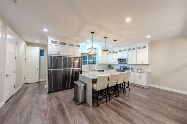 A modern kitchen with white cabinets, stainless steel appliances, and a central island with bar stools.